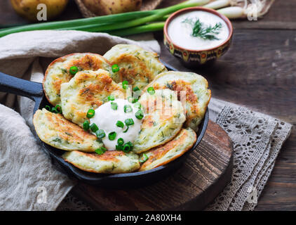 Des galettes de pommes de terre poêlées latkes dans iron skillet sur fond de bois rustique. La nourriture traditionnelle juive pour Hannukah célébration. Banque D'Images