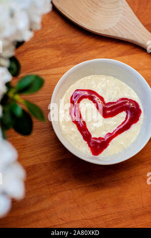 Savoureux et délicieux riz au lait avec un coeur de framboise rouge au milieu, sur une planche à découper en bois. Un dessert traditionnel de Noël en Finlande Banque D'Images