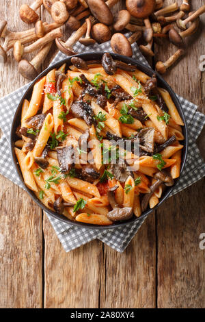 De délicieuses pâtes penne avec du miel d'automne champignons et sauce tomate close-up dans une assiette sur la table. Haut Vertical Vue de dessus Banque D'Images