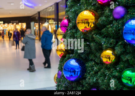 Les acheteurs de noël en passant devant un arbre de Noël décoré avec des boules lumineuses dans un centre commercial Banque D'Images