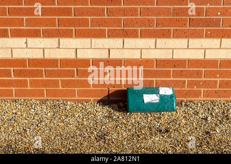 Un piège de rentokil pest control sur le terrain à l'extérieur d'un bâtiment en brique Banque D'Images