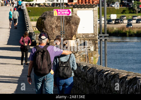 Couple en train de marcher sur un vieux pont dans le village de Ponte de Lima, Minho, Portugal, Europe Banque D'Images