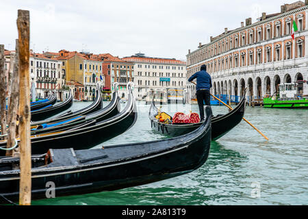 Un gondolier gondoles sa direction passé une ligne de bateaux amarrés sur le Grand Canal à Venise Italie Banque D'Images