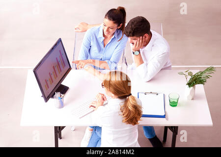 Top Shot of woman conseiller en investissements donnant une présentation d'un jeune couple souriant assis à son bureau dans le bureau. Banque D'Images