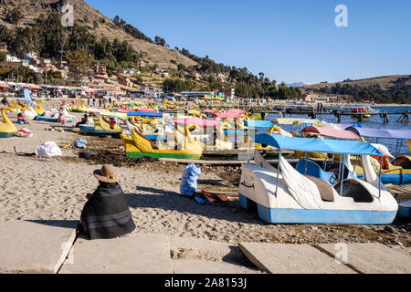 Vieille Femme assise locale avec de petits bateaux colorés sur la plage de Copacabana, Bolivie rive Banque D'Images