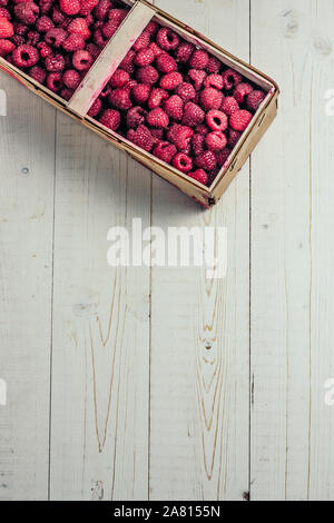 Baies sauvages - Framboises du marché dans une boîte en bois - vertical - copy space Banque D'Images