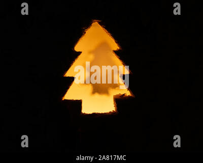 Forme d'arbre de Noël illuminé sur fond noir. La lumière des bougies floue brillant par l'irrégularité de la surface de l'objectif de la fenêtre de la lampe. Banque D'Images