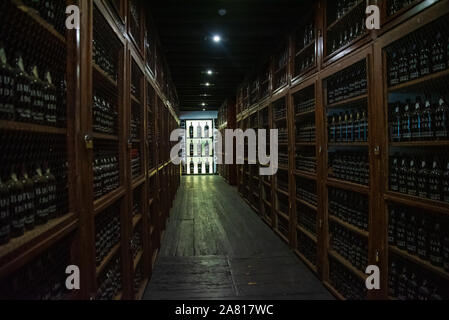 Une vue sur la cave à vin de Madère avec des rangées de bouteilles de vin stockées sur des étagères en bois, mettant en valeur le processus de vieillissement du vin dans un environnement traditionnel Banque D'Images