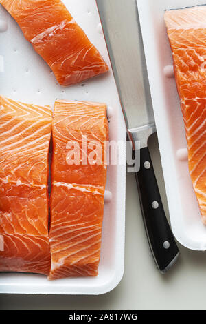 Le saumon frais, coupé en morceaux et prête pour la cuisson du poisson. la coupe et un grand couteau chef. Banque D'Images