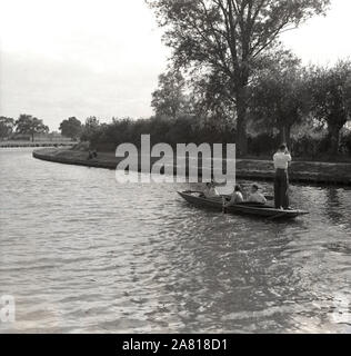 Années 1950, historique, deux couples voyageant le long de la rivière Cam sur un punt en bois, Cambridge, Angleterre, Royaume-Uni. L'un des messieurs se tient à la poupe du punt en utilisant un réglage ou un poteau de quantité pour pousser aganist le lit de la rivière pour propulser le bateau vers l'avant, une action connue sous le nom de punting. Banque D'Images