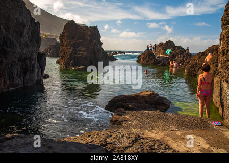 Vue panoramique sur les piscines volcaniques naturelles de Porto Moniz, Madère, avec de l'eau turquoise claire et des vagues qui s'écrasent sur les rochers Banque D'Images