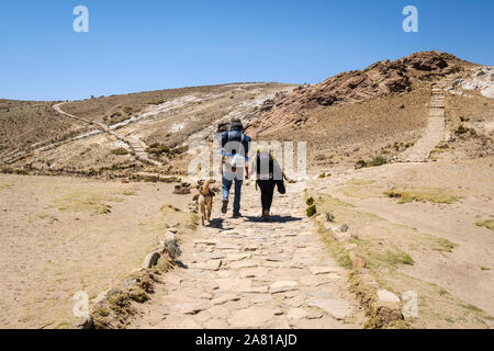 Couple de touristes routards sur le chemin qui mène à l'extrémité nord de l'île du soleil sur l'Challa Communauté dans le lac Titicaca, en Bolivie Banque D'Images