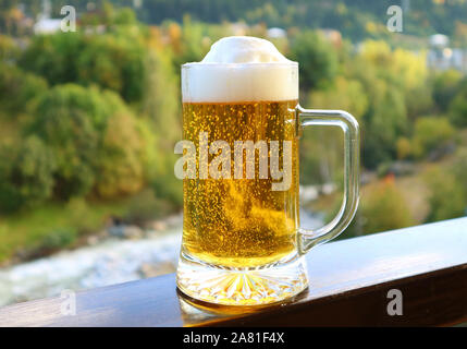 Une pinte de bière sur le balcon balustrade avec vue sur forêt floue Banque D'Images