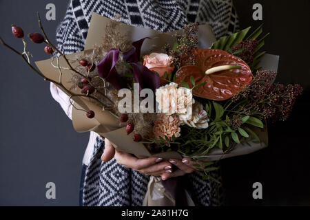 Les mains tenant un bouquet décorées en style vintage sur un fond sombre, selective focus Banque D'Images
