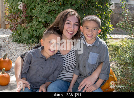 Une belle jeune femme assise avec ses deux garçons sur un joli jour d'automne Banque D'Images