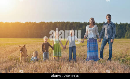 Une grande famille est aligné et avec un chien pose devant l'appareil photo. Banque D'Images