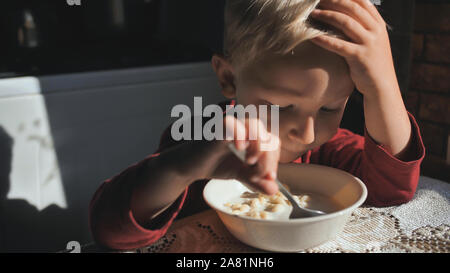 L'enfant mange de la soupe de pâtes de lait pour le petit-déjeuner. Banque D'Images