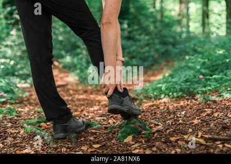 Female hiker avec blessure à la cheville en forêt à l'extérieur lors de l'activité de trekking, selective focus Banque D'Images