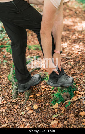 Female hiker avec blessure à la cheville en forêt à l'extérieur lors de l'activité de trekking, selective focus Banque D'Images