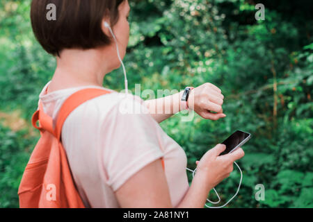 Female hiker remise en forme contrôle et synchronisation des données bracelet tracker à smartphone, image sélective Banque D'Images