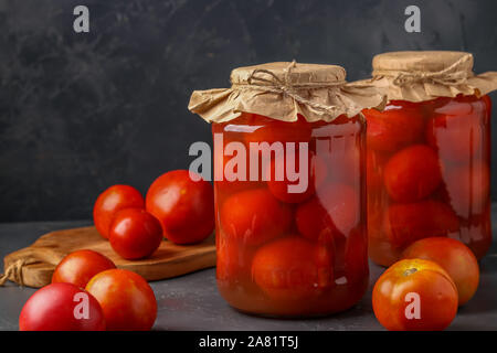 Des tomates salées en pots sur un fond sombre, les aliments fermentés, gros plan Banque D'Images