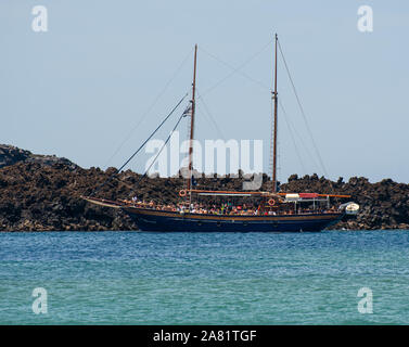 L'île de Néa Kaméni, Grèce - 16 juillet 2019 : visite guidée bateau amarré par le basalte volcanique de l'île de Nea Kameni Banque D'Images