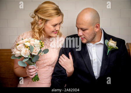 Close up of Bride and Groom en vêtements vintage assis et de toucher avec bride holding bouquet en attendant de se marier Banque D'Images