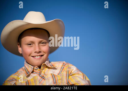 Portrait of a smiling Young boy wearing a cowboy hat au soleil. Banque D'Images