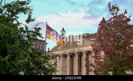 Le Reichstag et le drapeau allemand entourée d'arbres à Berlin, Allemagne Banque D'Images