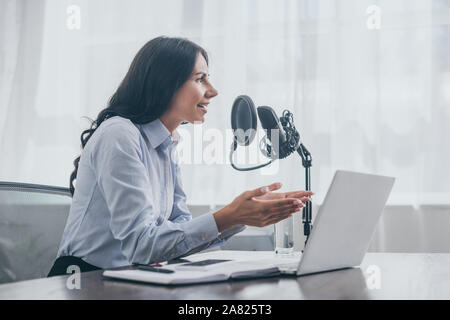 Smiling radio host gesticulant pendant l'enregistrement en studio de radio podcast Banque D'Images