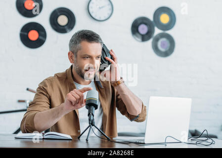 Handsome radio host holding réglage casque et microphone de studio de diffusion Banque D'Images