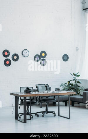 Spacieuses, meublées studio de radio avec un bureau en bois, les chaises de bureau et vinyles sur mur blanc Banque D'Images