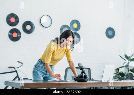 Jolie animateur de radio à la recherche à l'ordinateur en milieu de travail au comité permanent en studio de diffusion Banque D'Images