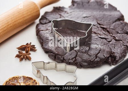 Pâte crue pour le chocolat biscuits de Noël près de rouleau à pâte et moisissures sur fond blanc Banque D'Images