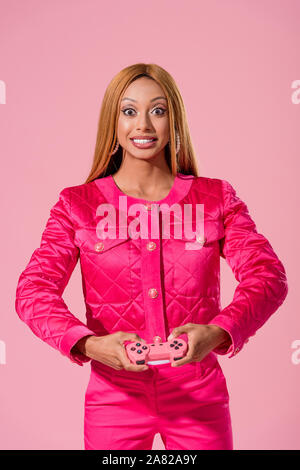 Kiev, UKRAINE - le 16 septembre 2019 : élégant, african american woman holding joystick isolé sur rose, concept Fashion poupée Banque D'Images