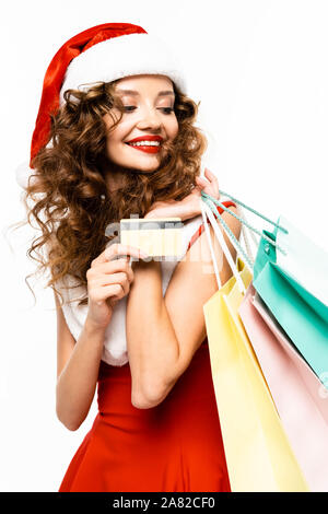 Beautiful smiling girl in santa costume holding shopping bags, une carte de crédit, isolated on white Banque D'Images