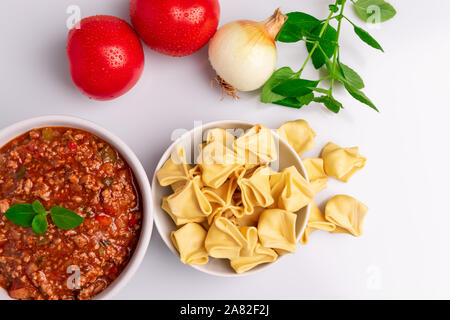 Tortellini Bolognaise avec pâtes Fagottini (savez également comme Bolognesa ou Bolonhesa) de sauce dans un bol blanc isolé en fond blanc, lumière douce, studio Banque D'Images