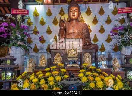 Da nang, Vietnam - 10 mars 2019 : Chua Long un temple bouddhiste chinois. Statue de Bouddha central en bois brun sur l'autel principal. Fleurs jaune d'or et d'o Banque D'Images