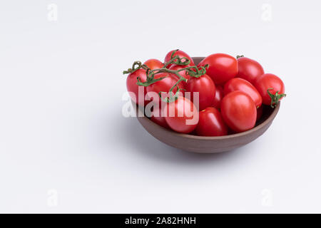 Tomate cerise raisin ou de branche. Tas de tomates raisin rouge brun dans un bol, isolé sur fond blanc Banque D'Images