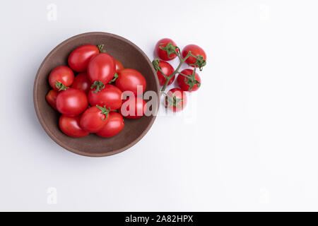 Tomate cerise raisin ou de branche. Tas de tomates raisin rouge brun dans un bol, isolé sur fond blanc Banque D'Images