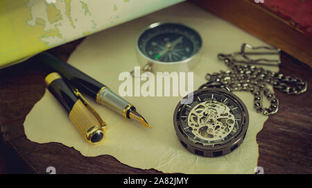 Montre de poche avec de vieux livres et stylo avec carte papier sur la table par la fenêtre. Concept de planification de voyage. Banque D'Images