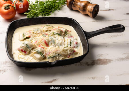 La couleur fait main ; pâtes Ravioli Ravioli pâtes multicolores dans une poêle de fer, noir sur blanc en bois fond de table. Banque D'Images