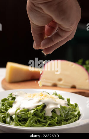 Des épinards fettucine greeen avec sauce béchamel dans une assiette blanche, table en bois rustique, d'arrière-plan lumière douce. Style de cuisine italienne Banque D'Images