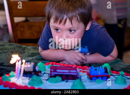 Un mignon petit garçon souffle les bougies sur son gâteau d'anniversaire Banque D'Images