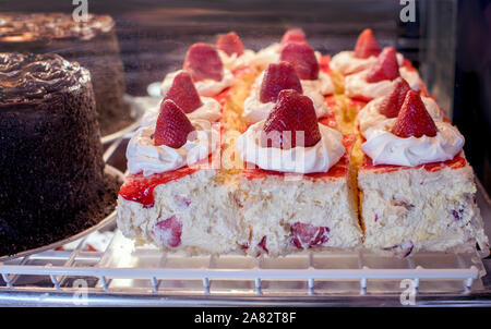 Delicious strawberry napoléons au frais dans un cas , assis à côté d'un immense gâteau au chocolat à ce restaurant local aux ETATS UNIS Banque D'Images