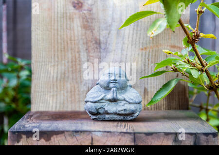 Bouddha en pierre de style thaï avec des mains qui prient dans un cadre zen Banque D'Images