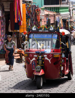 Un mototaxi, peu de transports publics, sur une rue pavée de Santiago Atitlan, Guatemala. Boutiques de souvenirs touristiques bordent la rue. Banque D'Images