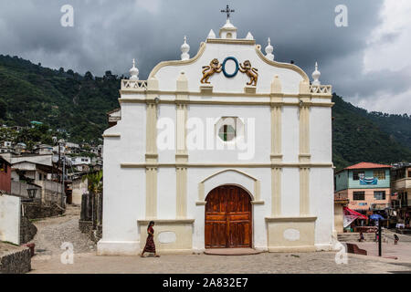 Une jeune femme maya en vêtements traditionnels promenades en face de l'église de Santa Catarina Palopo au Guatemala. Banque D'Images