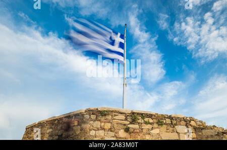 Brandir le drapeau grec contre le ciel bleu Banque D'Images