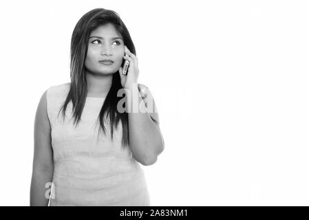 Studio shot of young woman persane gras tout en pensant talking on mobile phone Banque D'Images